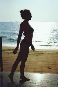 Full length of woman in bikini standing at beach