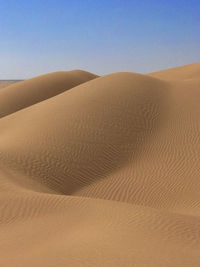 Sand dunes in desert against clear sky