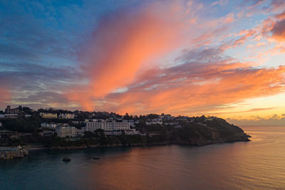 Scenic view of sea and buildings against sky during sunset