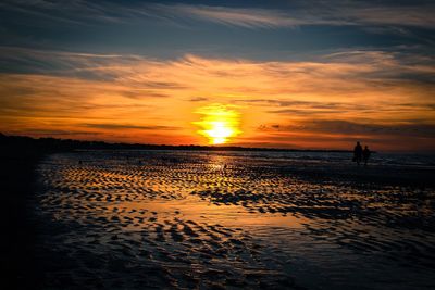 Scenic view of beach against orange sky