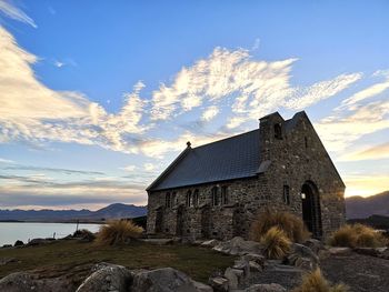 Historic small chapel by the lake against sky at sunrise
