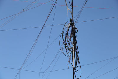 Low angle view of electricity pylon against clear blue sky