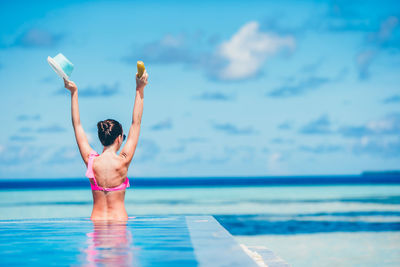 Full length of young man in swimming pool against sea