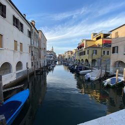 Canal amidst buildings in city against sky