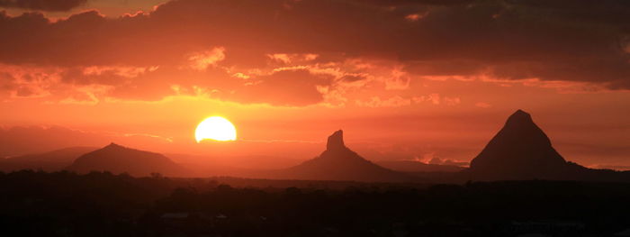 Scenic view of silhouette mountains against orange sky