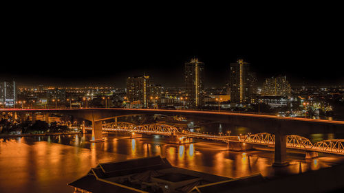 Illuminated bridge over river against sky at night