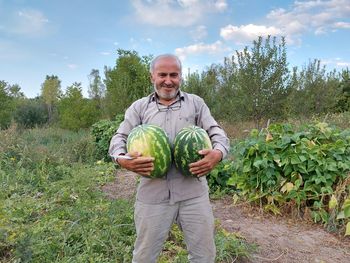 Portrait of man holding watermelon at farm