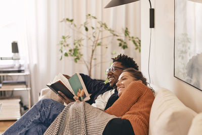 Happy couple enjoying reading books on sofa at home