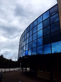 Low angle view of modern building against cloudy sky