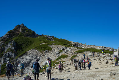 People on mountain against clear blue sky