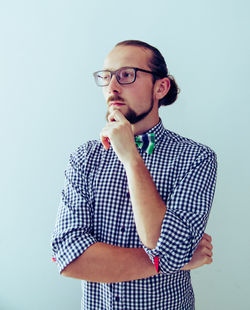 Man looking away while wearing eyeglasses against blue background