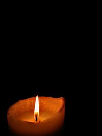 Close-up of illuminated candle in darkroom