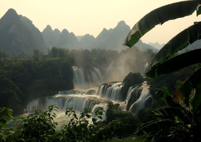 Scenic view of waterfall in forest against clear sky