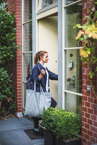 Female entrepreneur with bag entering in house