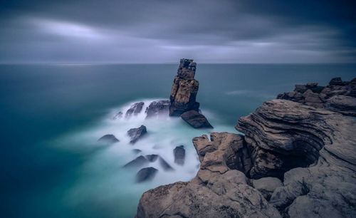 Rock formation in sea against sky