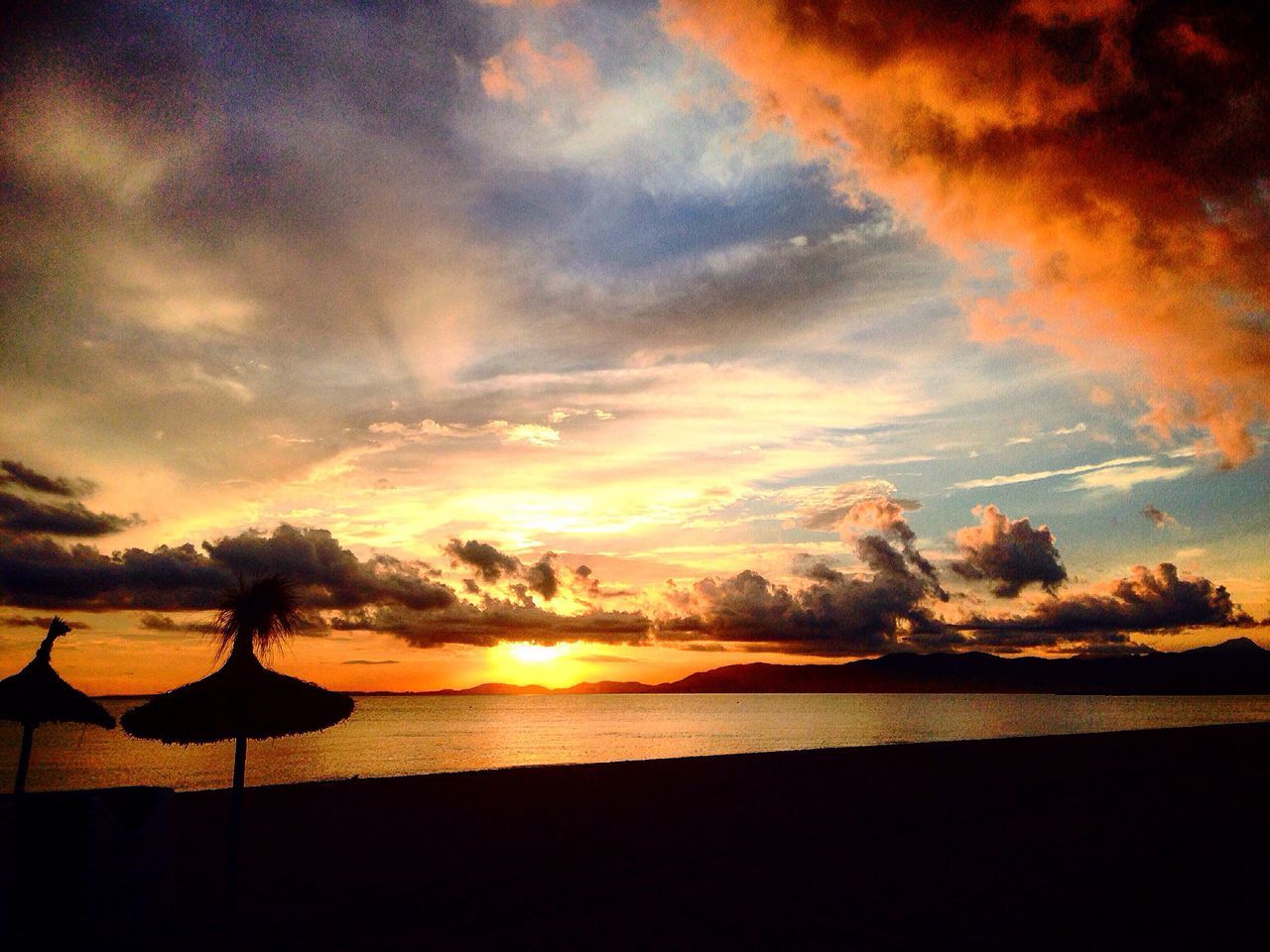 sunset, water, tranquil scene, scenics, silhouette, beauty in nature, sea, tranquility, idyllic, beach, cloud, majestic, calm, sky, orange color, nature, sunshade, atmospheric mood, outdoors, outline, cloud - sky, remote, shore, dramatic sky, solitude, sun, moody sky, ocean, cloudscape