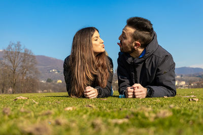Couple kissing on field against sky