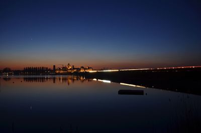 Illuminated city against clear sky at night