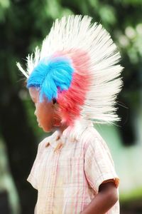 Close-up of boy wearing colorful wig while standing at park