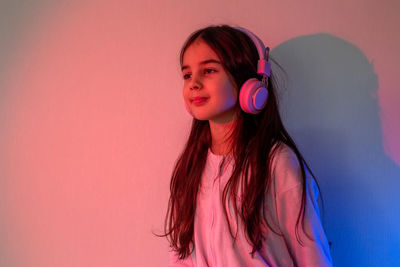 Little girl in headphones stand in neon light
