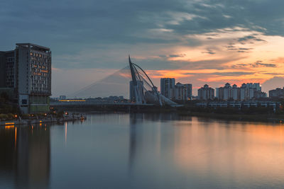 View of suspension bridge with city in background at sunset