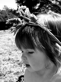 Close-up of cute baby girl wearing flowers in park during sunny day