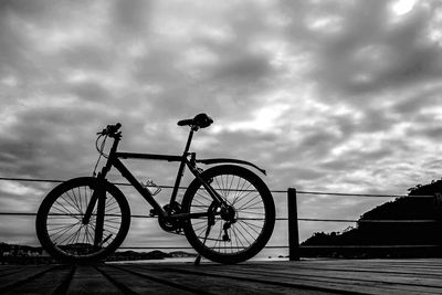 Bicycle parked against cloudy sky