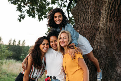 Portrait of smiling female friends near tree trunk