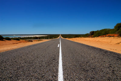 Empty road against clear blue sky