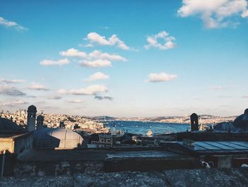 Cityscape by sea against blue sky