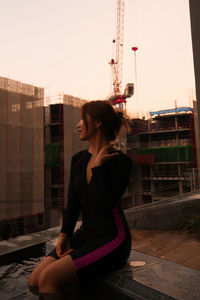Side view of young woman sitting on street