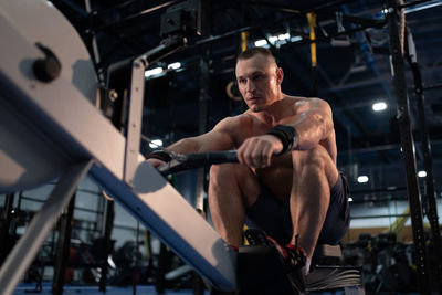 Powerful sportsman exercising on rowing machine