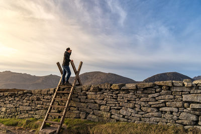 Full length of man climbing on ladder against sky