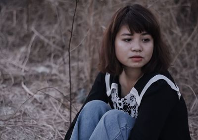 Portrait of young woman sitting on field