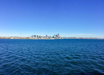 Scenic view of sea and buildings against clear blue sky