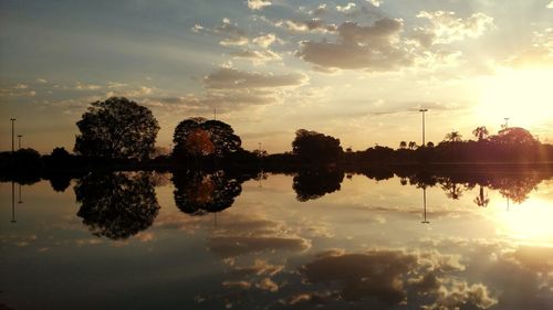 Reflection of silhouette trees in lake against sky during sunset