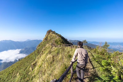 Rear view of man on mountain against blue sky