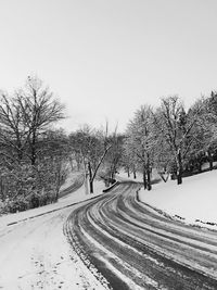 Road amidst trees against clear sky during winter