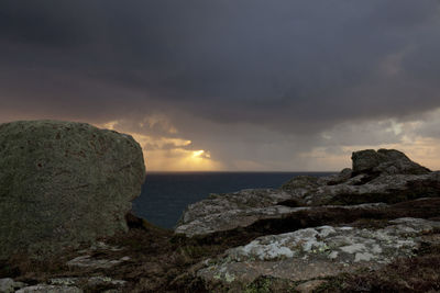 Rock formations by sea against sky during sunset