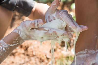 Midsection of person hands covered with liquid