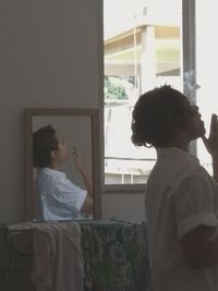 Young woman looking through window