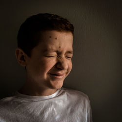 Boy with eyes closed smiling at home