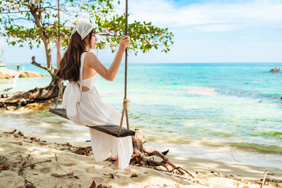 Young woman at beach against sky