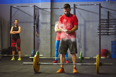 Full length of man standing by barbell at gym