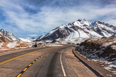 Road amidst snowcapped mountains against sky