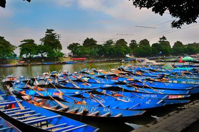 Multi colored boats moored in lake against blue sky