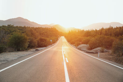 Country road by mountains against sky