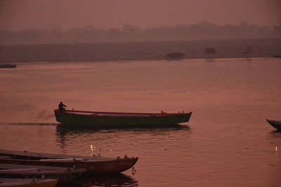 Boat moored in sea against sky during sunset