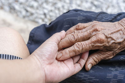 Close-up of old and young holding hands. middle-aged mommy's wrinkled hands holding young daughters