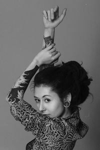 Portrait of young woman standing against wall